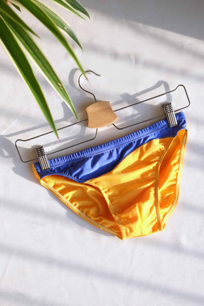 Vintage 80's Swim Briefs Low Rise with Bold Blue & Yellow displayed on a hanger against a white background.