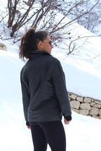 A woman standing in a snowy landscape wearing the vintage black Mossant Rangoon ski jacket, showing the fit and mid-length cut from behind.