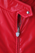 A tight macro shot of the red Mossant ski jacket’s central zipper. The silver-tone zipper pull is embossed with the Mossant brand crest, featuring a winged horse (Pegasus) design.
