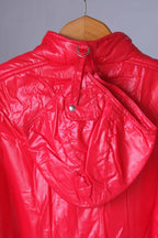 The rear view of the red Mossant jacket on a wooden hanger, highlighting the detachable hood. The hood is attached to the collar via a strap and metal D-ring system with a snap-button closure.