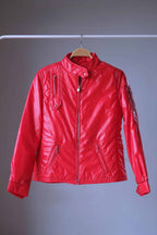 Full front view of a vibrant red vintage 1970s Mossant technical ski jacket on a wooden hanger. It features a quilted nylon shell, an asymmetrical snap collar, two slanted waist pockets, and a vertical chest pocket.
