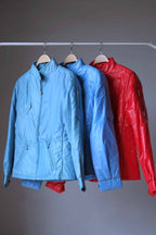 Three vintage Mossant technical ski jackets hanging in a row on a clothing rack, showcasing the available colorways: sky blue, steel blue, and bright red. The shot emphasizes the consistent "Natacha" model design across different colors.