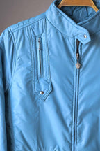 Detailed shot of the sky blue Mossant jacket's neckline and zipper. The high collar is secured with a silver snap, and the zipper pull features the signature Mossant Pegasus crest.