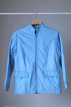 A front-facing shot of an azure blue 1970s Mossant ski jacket on a wooden hanger, featuring a full-length zipper and two large front flap pockets.