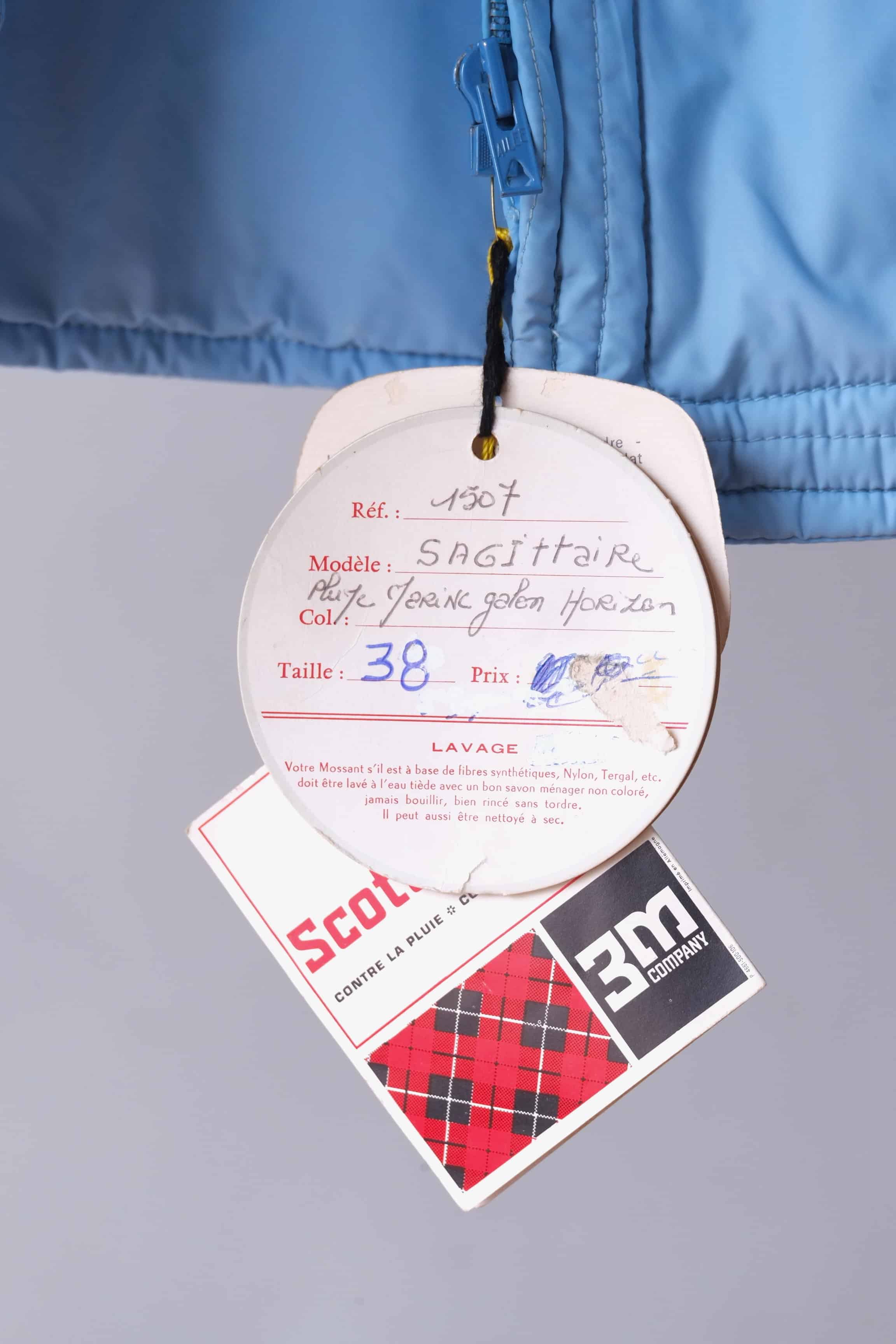 Close-up of the original vintage tags on the jacket, showing the handwritten model name, reference number and size. Also visible the Scotchgard 3M trademark.