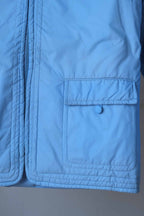 Detail shot of the jacket’s front square flap pocket, featuring tonal blue stitching and a decorative fabric-covered button.