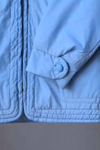 Close-up of the jacket's lower hem and sleeve cuff, showing the multi-row horizontal topstitching and a button-closure cuff detail.