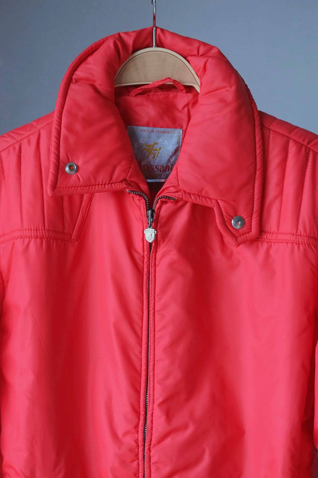 A close-up of the upper chest and collar, showing the "Made in France" Mossant label, the silver-tone shield zipper pull, and the snap-down collar points.