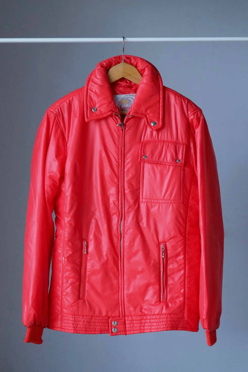 Full front view of a vibrant red vintage 70s Mossant high-shine ski jacket on a wooden hanger, featuring a large pointed collar and a distinctive snap-button chest pocket.