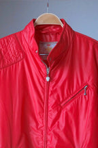 Close-up of the upper half of the red Mossant jacket, showing the quilted shoulder padding, stand-up collar, and a diagonal zippered chest pocket.