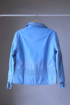 The full rear view of a vintage sky-blue Mossant Aral ski jacket on a wooden hanger, featuring smocked ribbing across the waist and a matching ribbed collar.