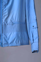 A close-up of the jacket's lower front and sleeve, showing a zippered hip pocket, smocked waist band, and a small utility pocket on the forearm with a snap closure.