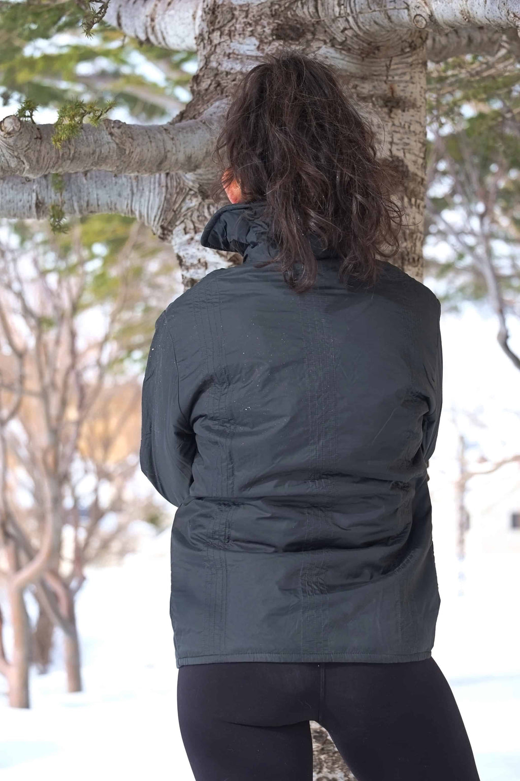 Back view of the vintage 70s Mossant black ski jacket worn by a female model in a snowy outdoor setting, highlighting the textured quilting.