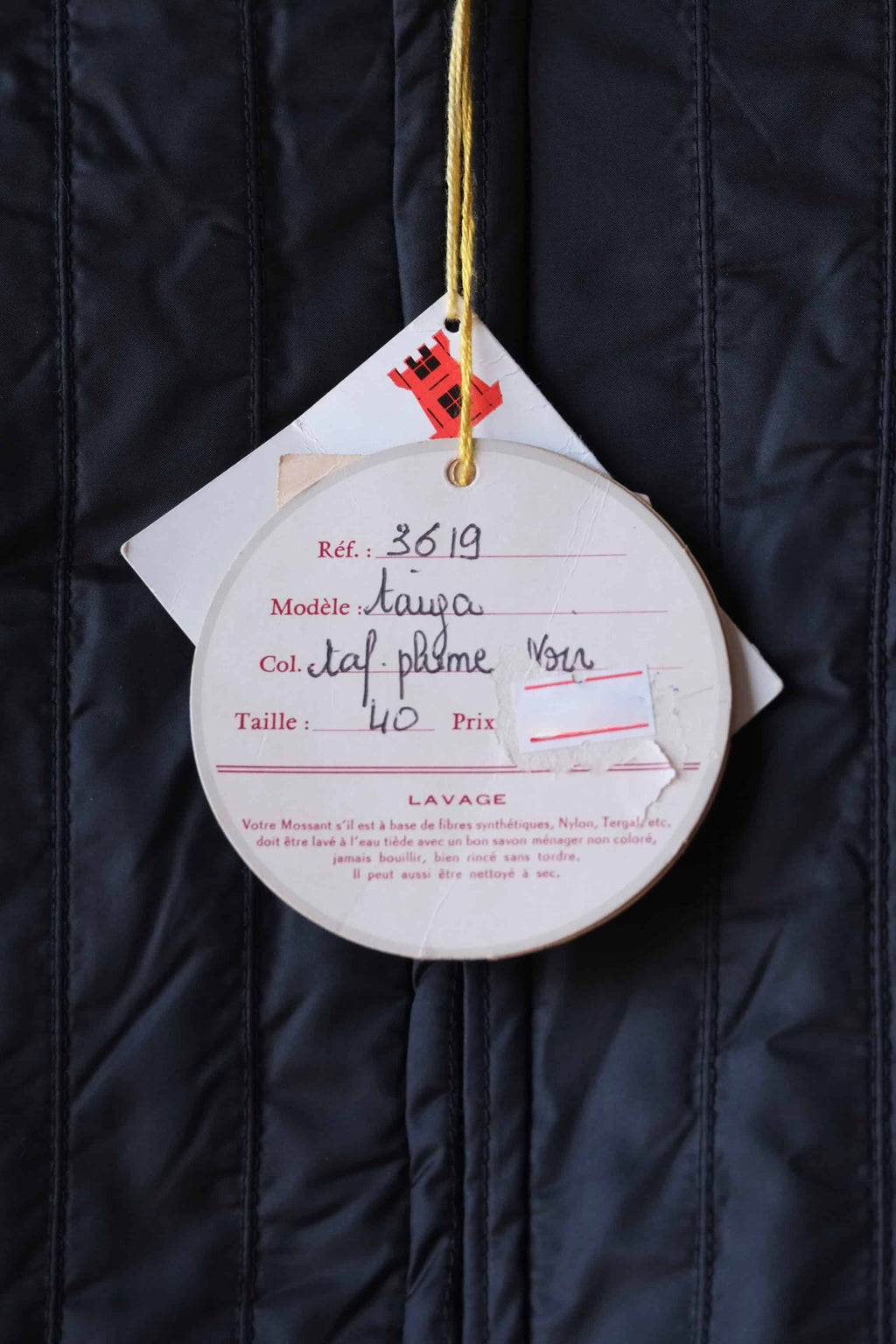 Close-up on the original paper hangtags for a Mossant Paris jacket. The labels show the handwritten jacket details, the reference, the model name, the color and the size.