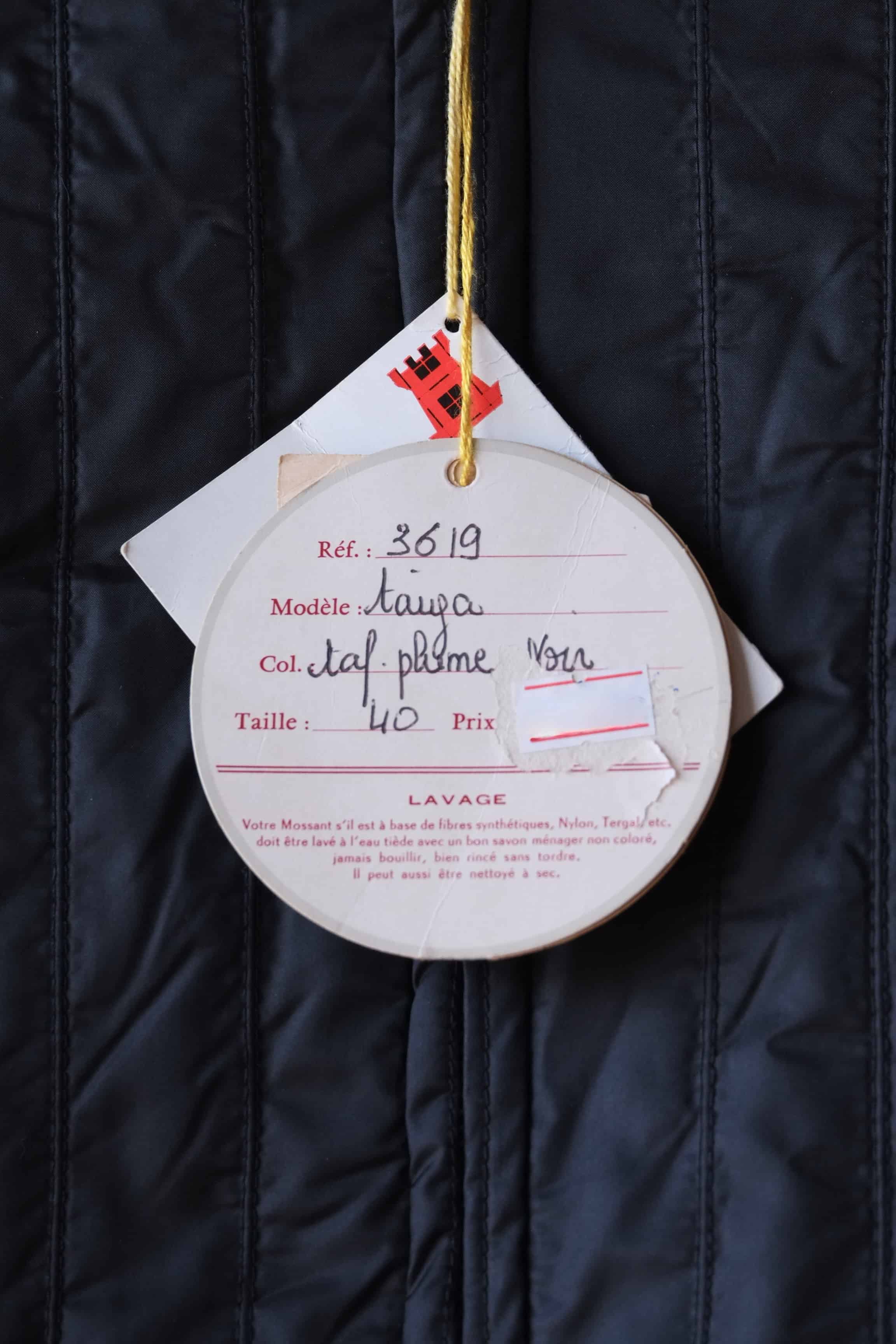 Close-up on the original paper hangtags for a Mossant Paris jacket. The labels show the handwritten jacket details, the reference, the model name, the color and the size.