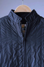 Close-up detail of the upper chest and collar of a black vintage Mossant ski jacket. The image highlights the precise vertical channel quilting, the sturdy black plastic zipper, and the high-neck collar construction.