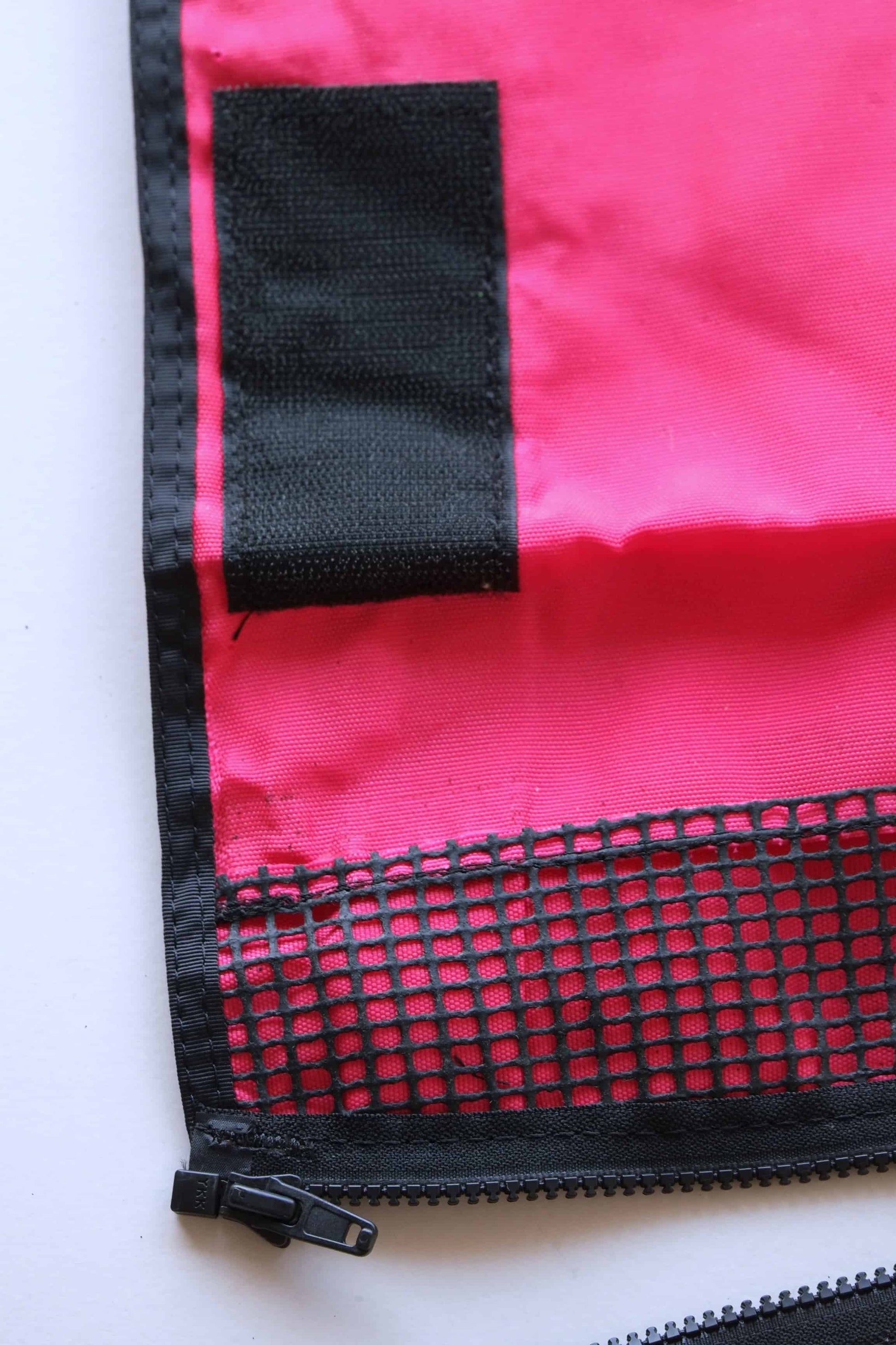 Close up of a red pocket, we can see part of the zipper and the velcro patch.