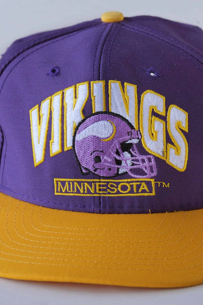 close view of purple and yellow minnesota vikings nfl snapback hat on white background