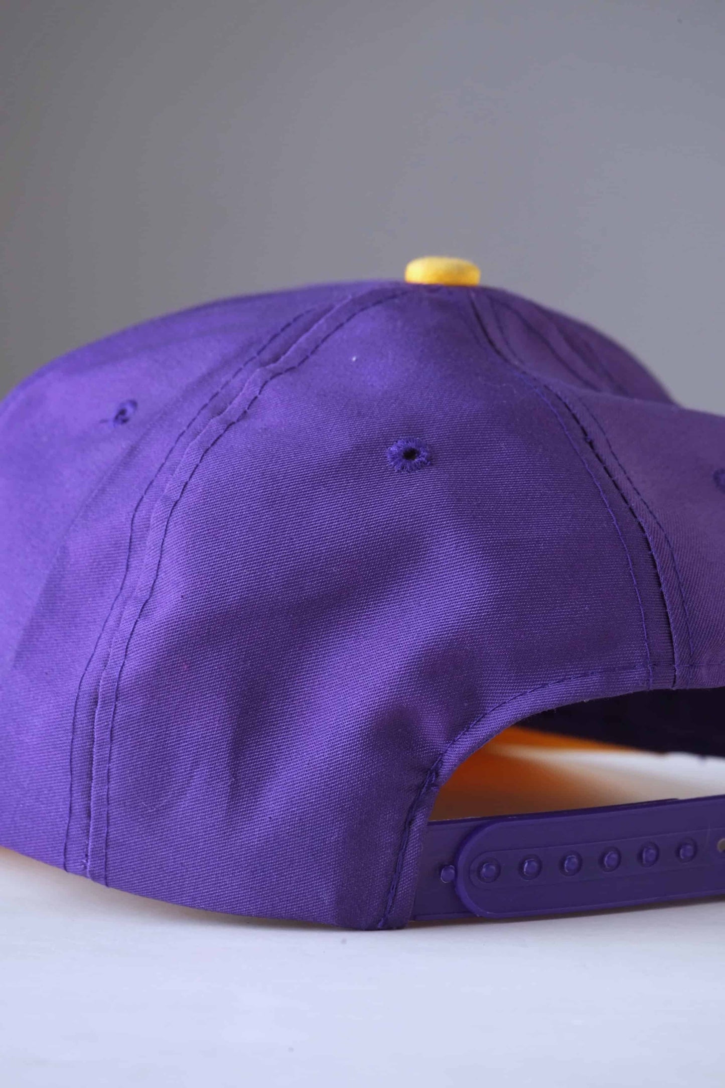 back view of purple and yellow minnesota vikings nfl snapback hat on white background
