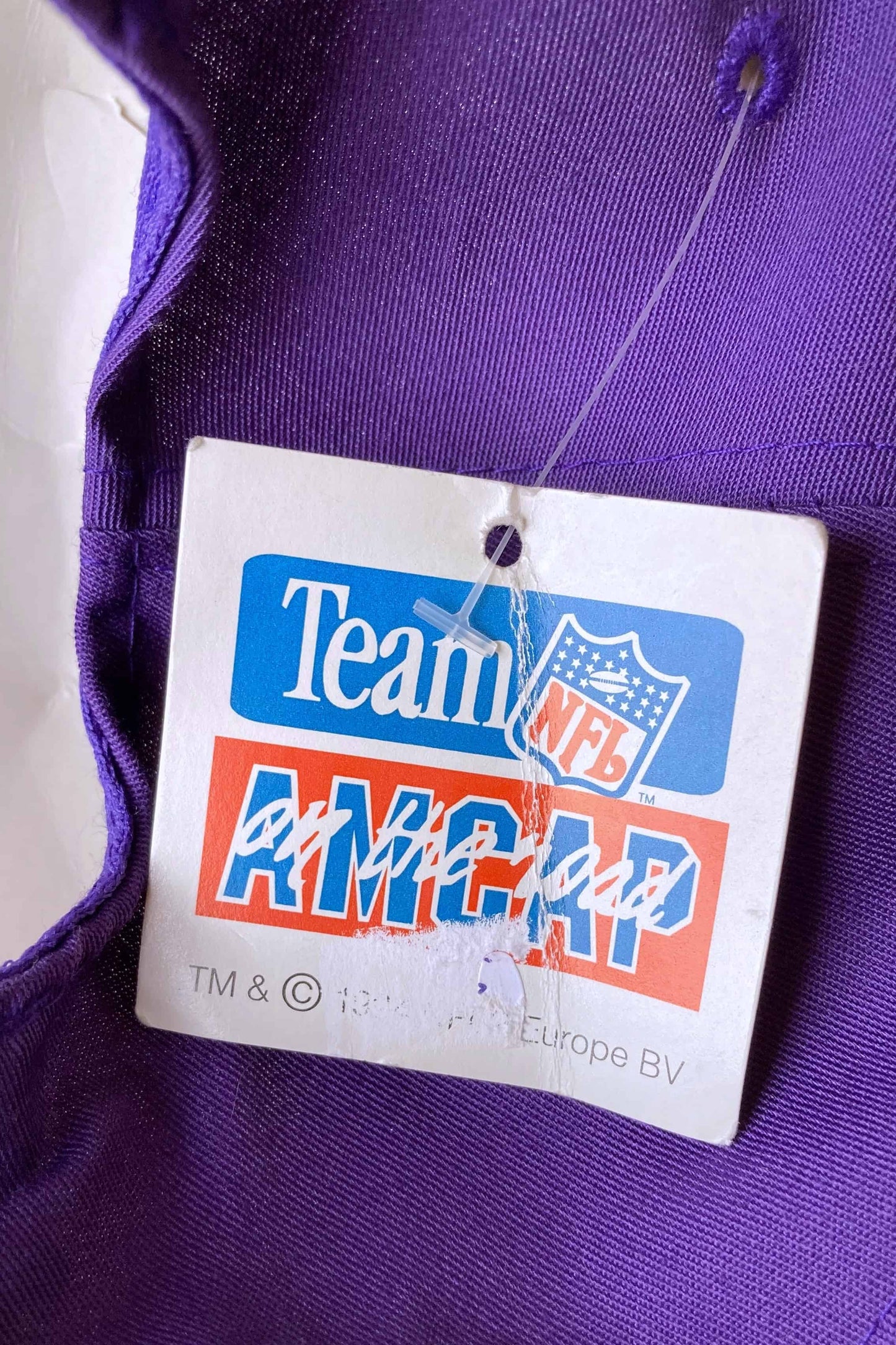 close up of an NFL tag on a purple and yellow minnesota vikings nfl snapback hat on white background