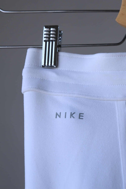 Close-up of the Nike logo on the back waistband of a pair of white pants.  The logo is in a silver color and is printed on.