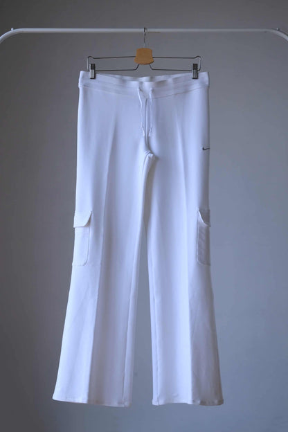 Vintage white Nike flare pants with cargo pockets and drawstring waist displayed on a hanger.