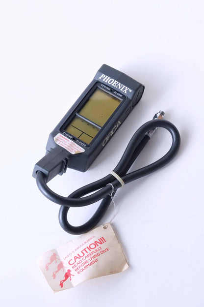 ORCA PHOENIX Air Integrated Scuba Dive Computer displayed on a neutral background. The tube is shown tied and a label is hanging from it.