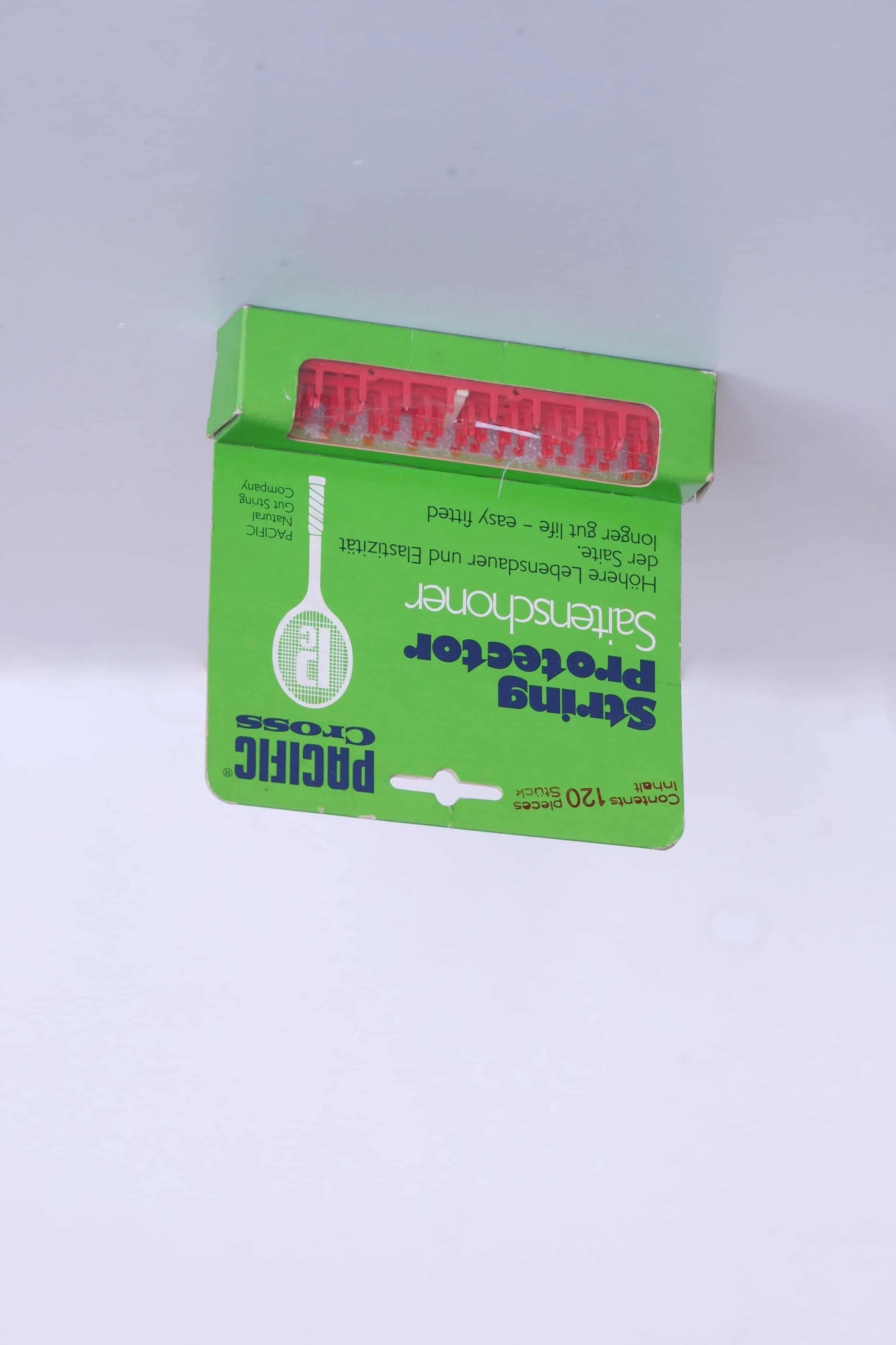 Vintage Pacific Cross string protectors in red, displayed in their original bright green retail card packaging.