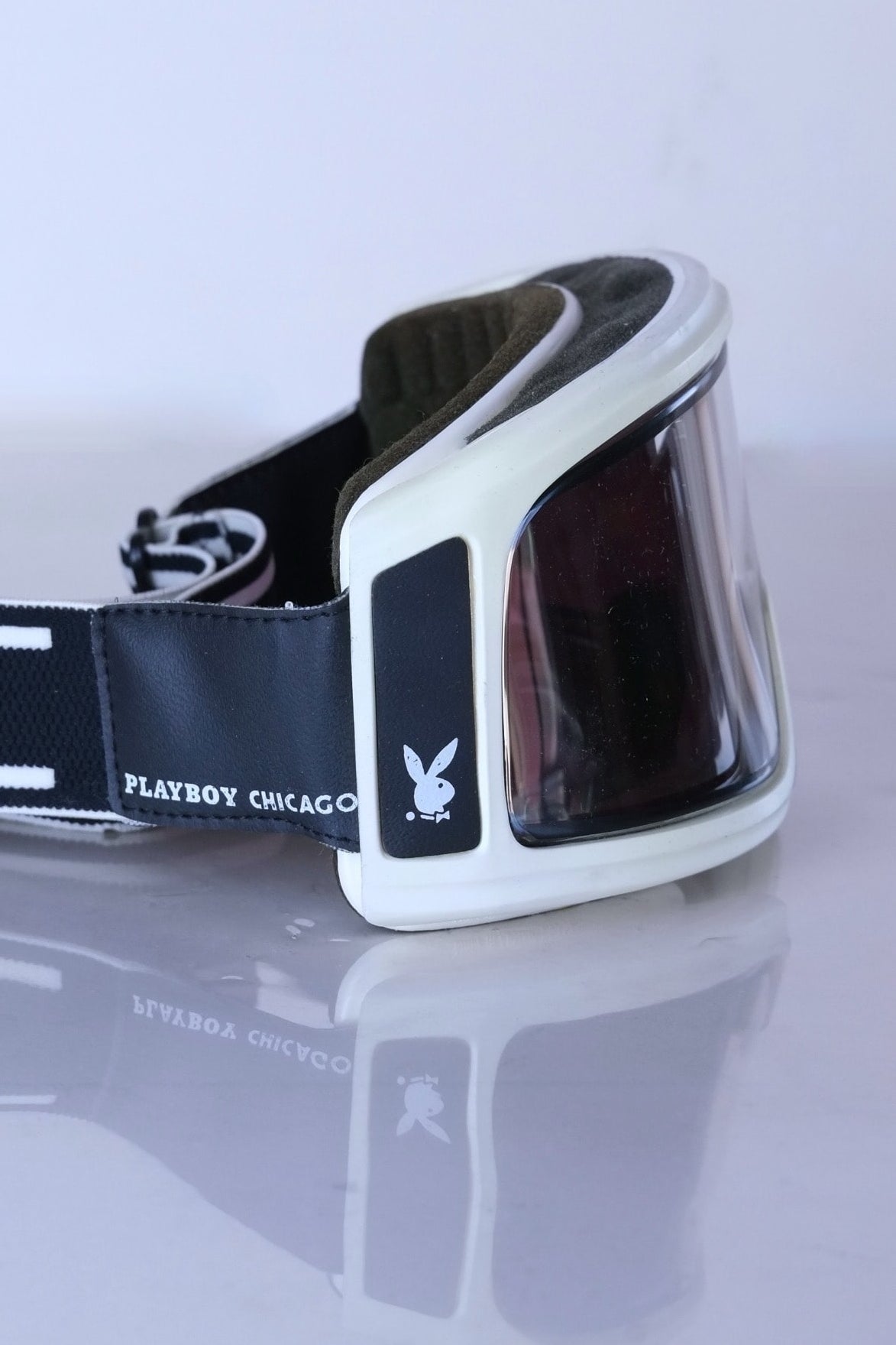 Close Side view of white Playboy Chicago ski goggles highlighting the rabbit head logo and intact interior foam.