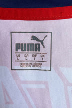 Close-up of the square, heat-pressed size label located on the inner neck. It features the classic Puma logo, text reading "US L / D/I L / E/F L / UK L", and "HECHO EN MEXICO / MADE IN MEXICO" stamped below the sizing grid against the white jersey fabric.
