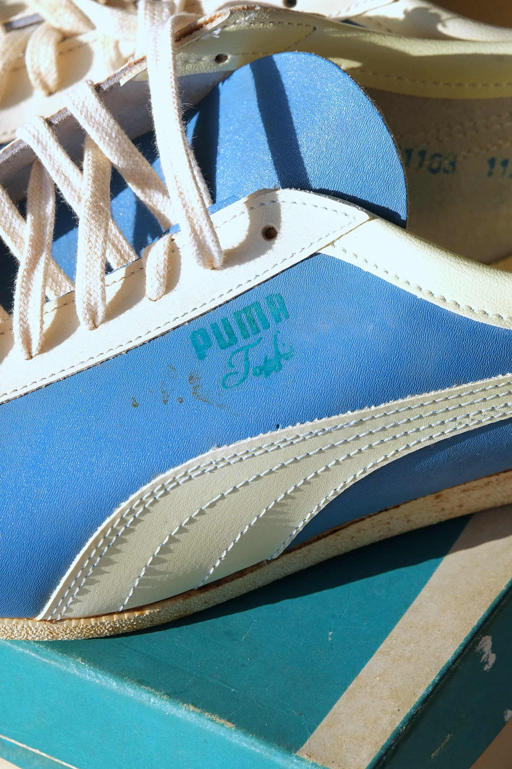 Detailed side view showing cream leather formstrip and teal Puma Top Fit branding on blue 1970s sneaker upper.