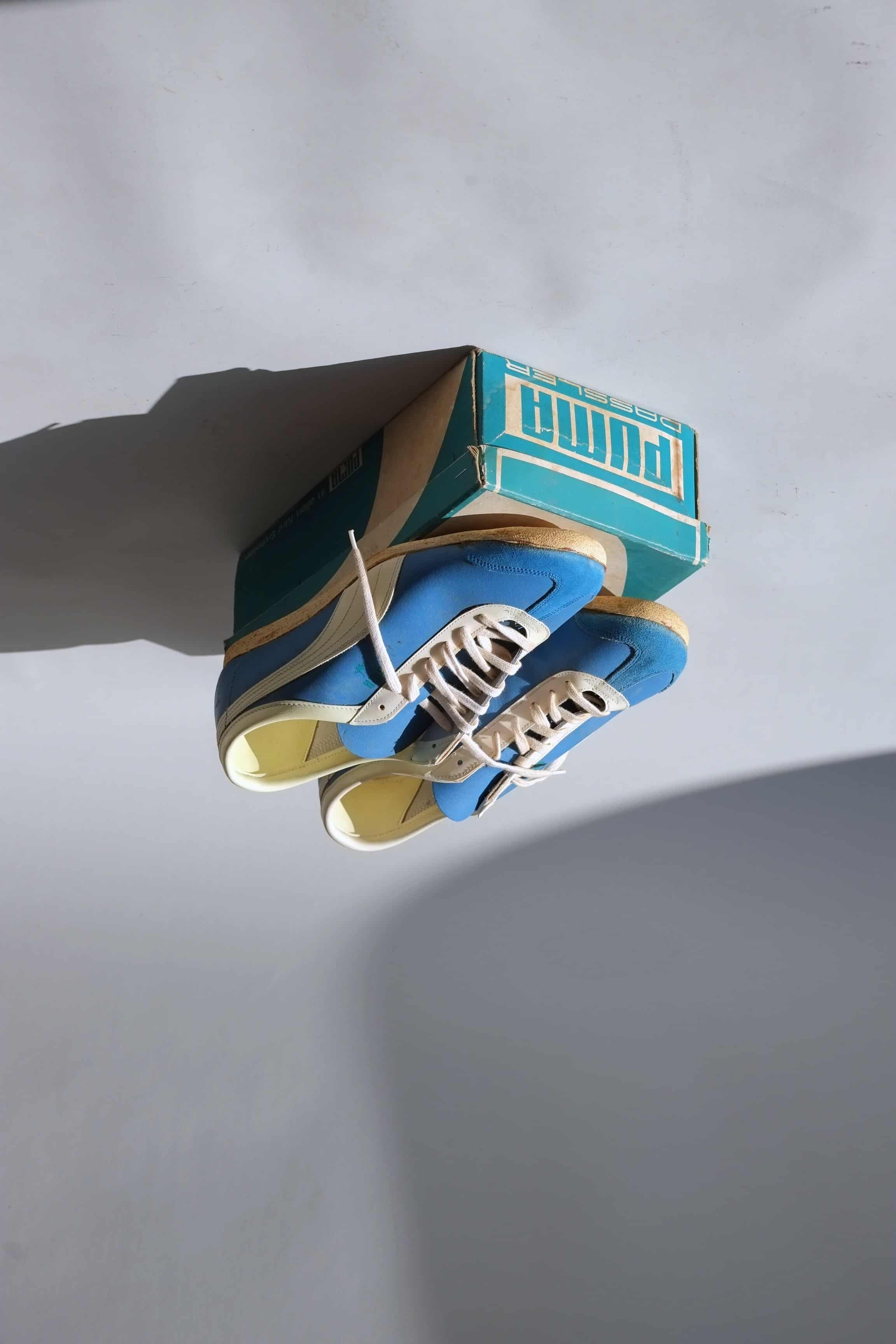 Three-quarter front view of vintage 1970s Puma Top Fit deadstock blue leather trainers displayed on original box.