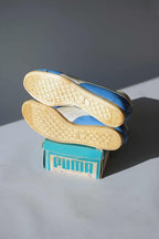 Underside view of intact yellow crepe rubber soles stacked on original teal Puma Dassler box showing model 112 Top-fit size 12 label.