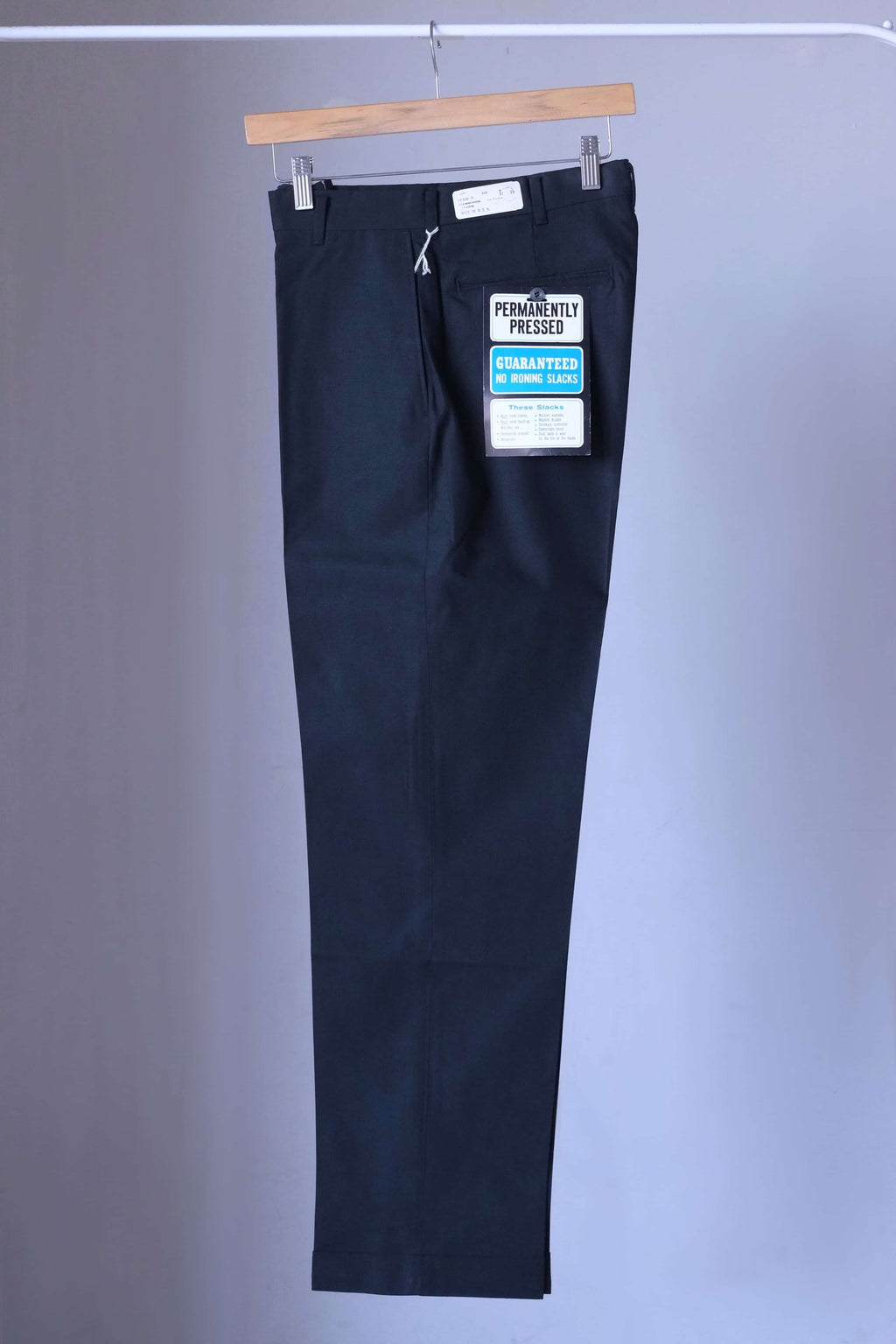 Side profile of a black pair of vintage Permanent Press tapered slacks showing the slim 70s silhouette and wrinkle-resistant fabric.