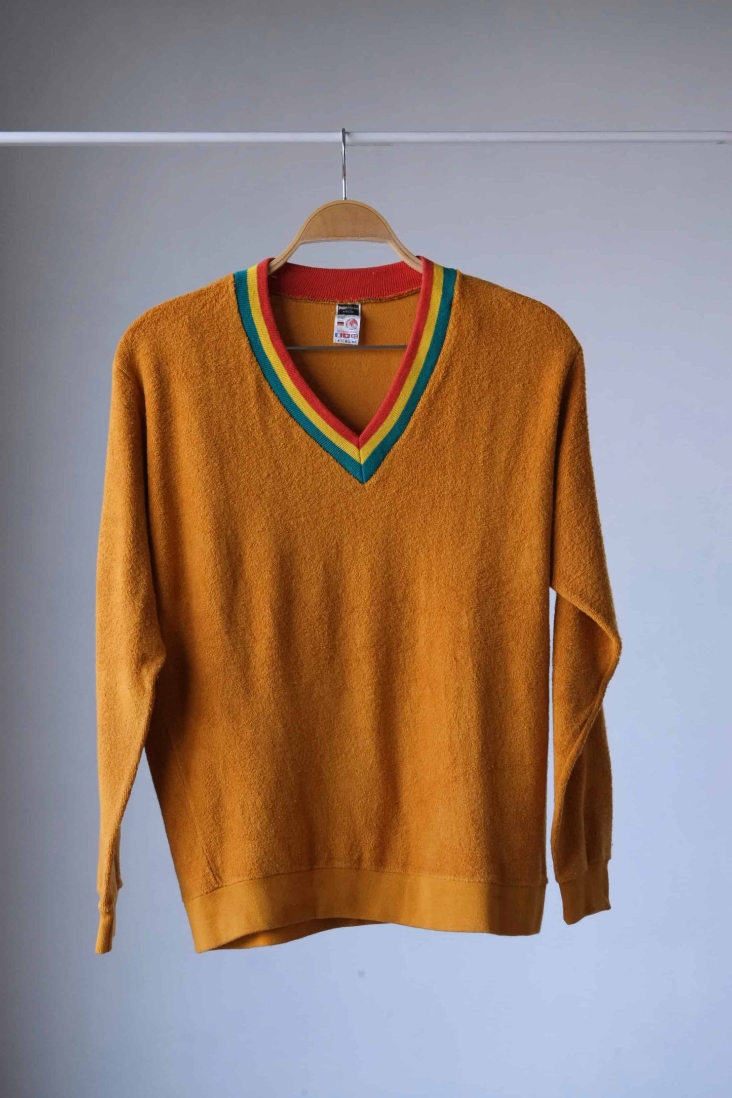 Restosana Vintage 70s Mustard Terrycloth Sweater with Colorful Striped Neckline displayed on a hanger against a grey background.