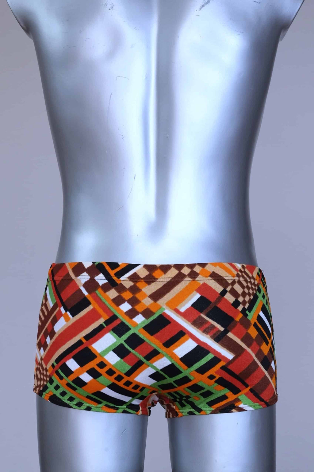 Back view of vintage 70s Ribana swim trunks in a geometric print with warm tones of orange, brown, green, and black, modeled on a silver mannequin.