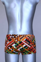 Back view of vintage 70s Ribana swim trunks in a geometric print with warm tones of orange, brown, green, and black, modeled on a silver mannequin.