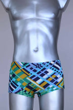 Front view of vintage 70s Ribana swim trunks in a geometric print with cool tones of blue, green, yellow, and navy, modeled on a silver mannequin.
