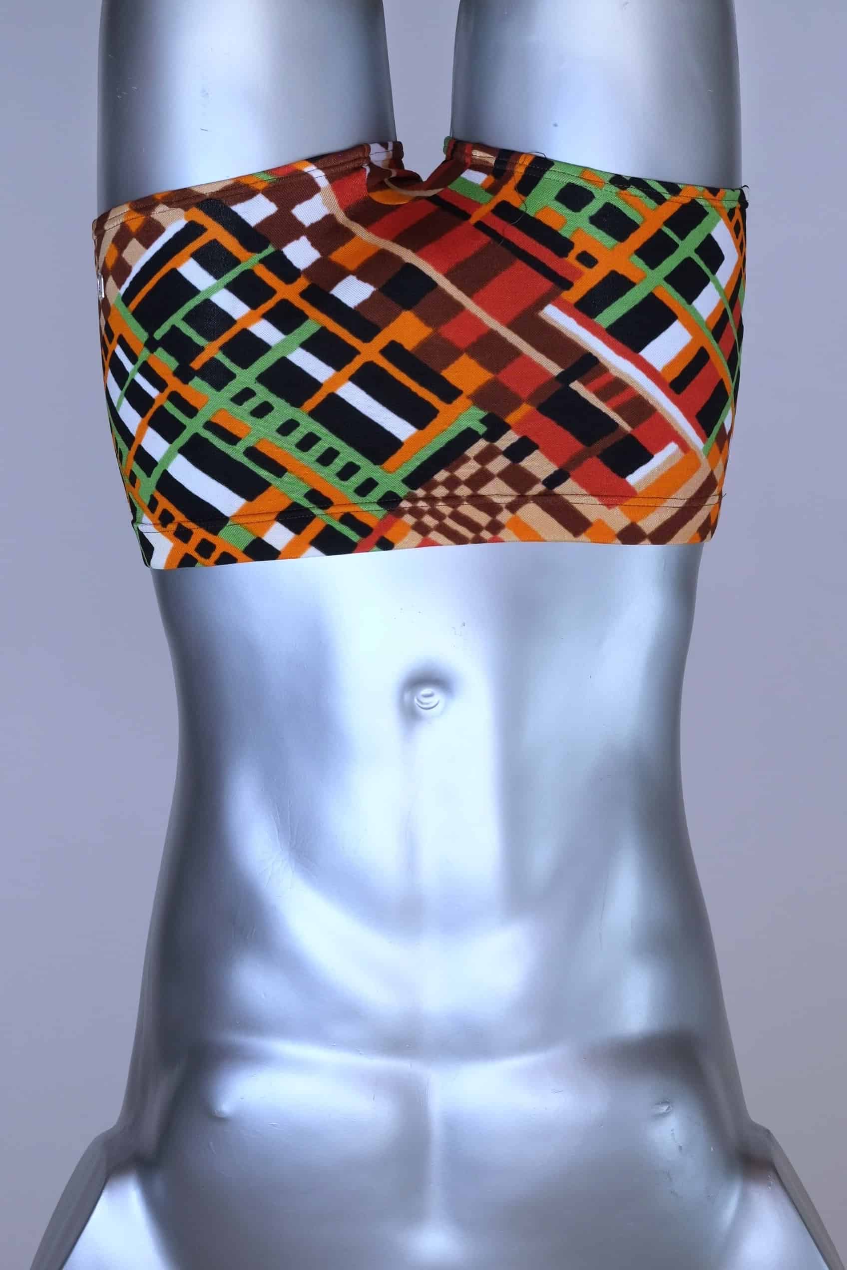 Front view of vintage 70s Ribana swim trunks in a geometric print with warm tones of orange, brown, green, and black, modeled on a silver mannequin.