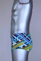 Side view of vintage 70s Ribana swim trunks in a geometric print with cool tones of blue, green, yellow, and navy, modeled on a silver mannequin.