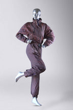 A full-body shot of a mannequin wearing a brown 90s vintage ski suit with a subtle orange abstract pattern, it has one leg raised.