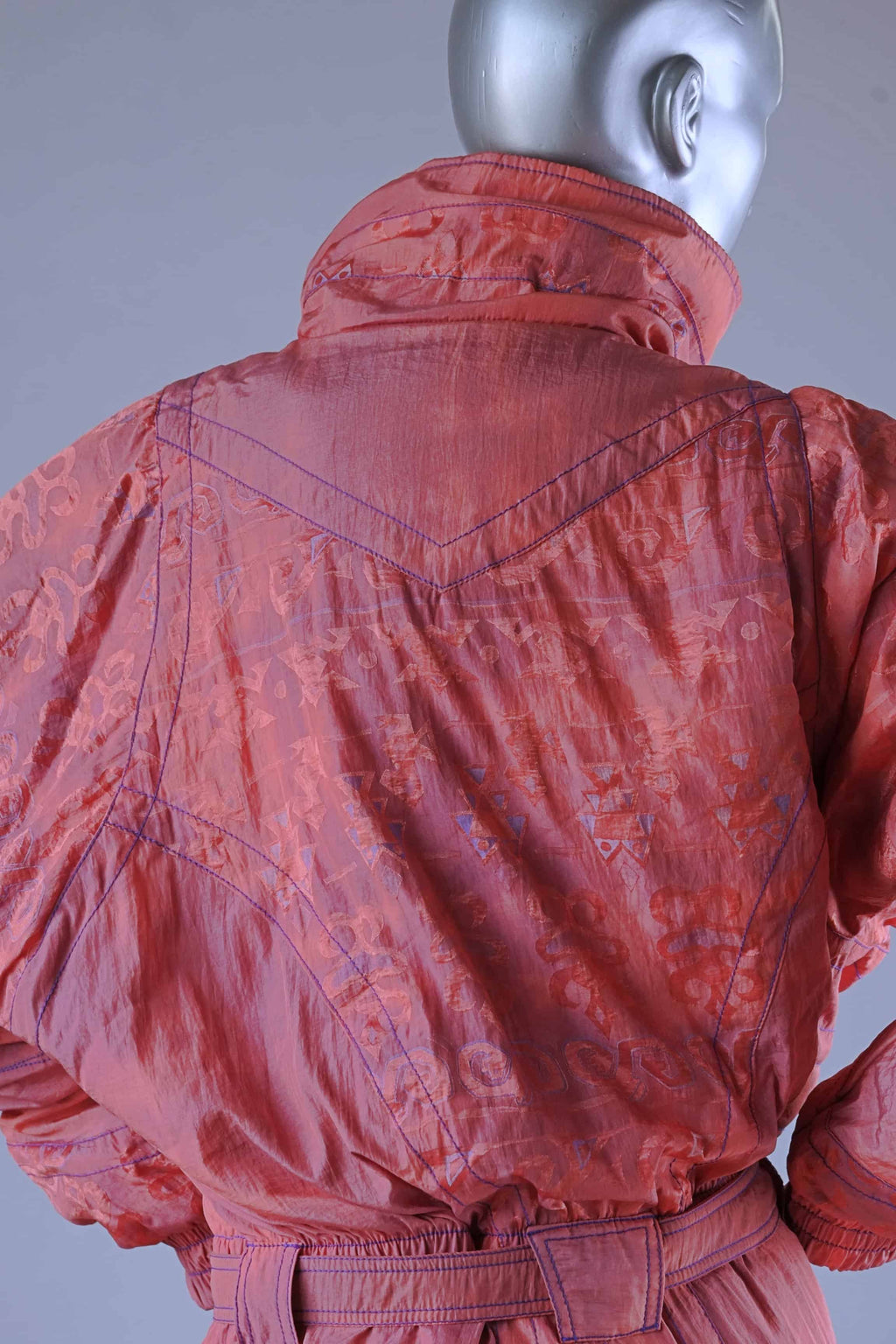 Back detail of a 90s coral ski suit showing stitching, subtle pattern, and collar.
