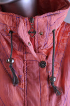 Detailed view of a coral 90s ski suit collar, showing a zipper, snap closures, drawstrings, and a 'Skin' brand zipper pull.