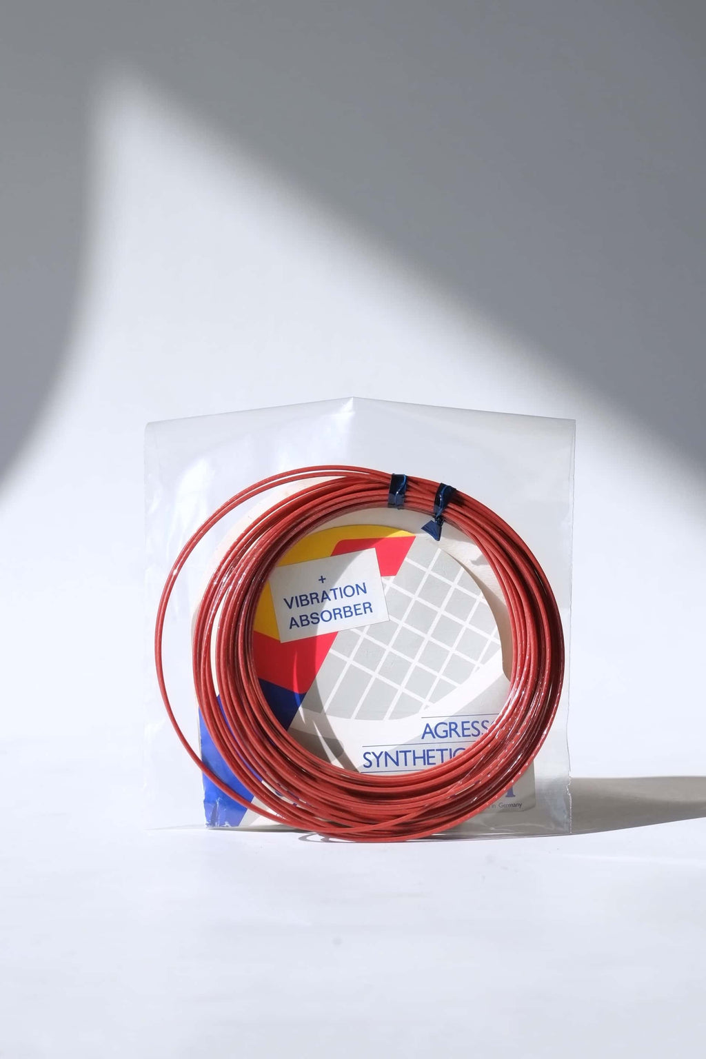 Coiled vintage Snauwaert Agressor synthetic gut tennis strings removed from the packaging to show the texture and color.