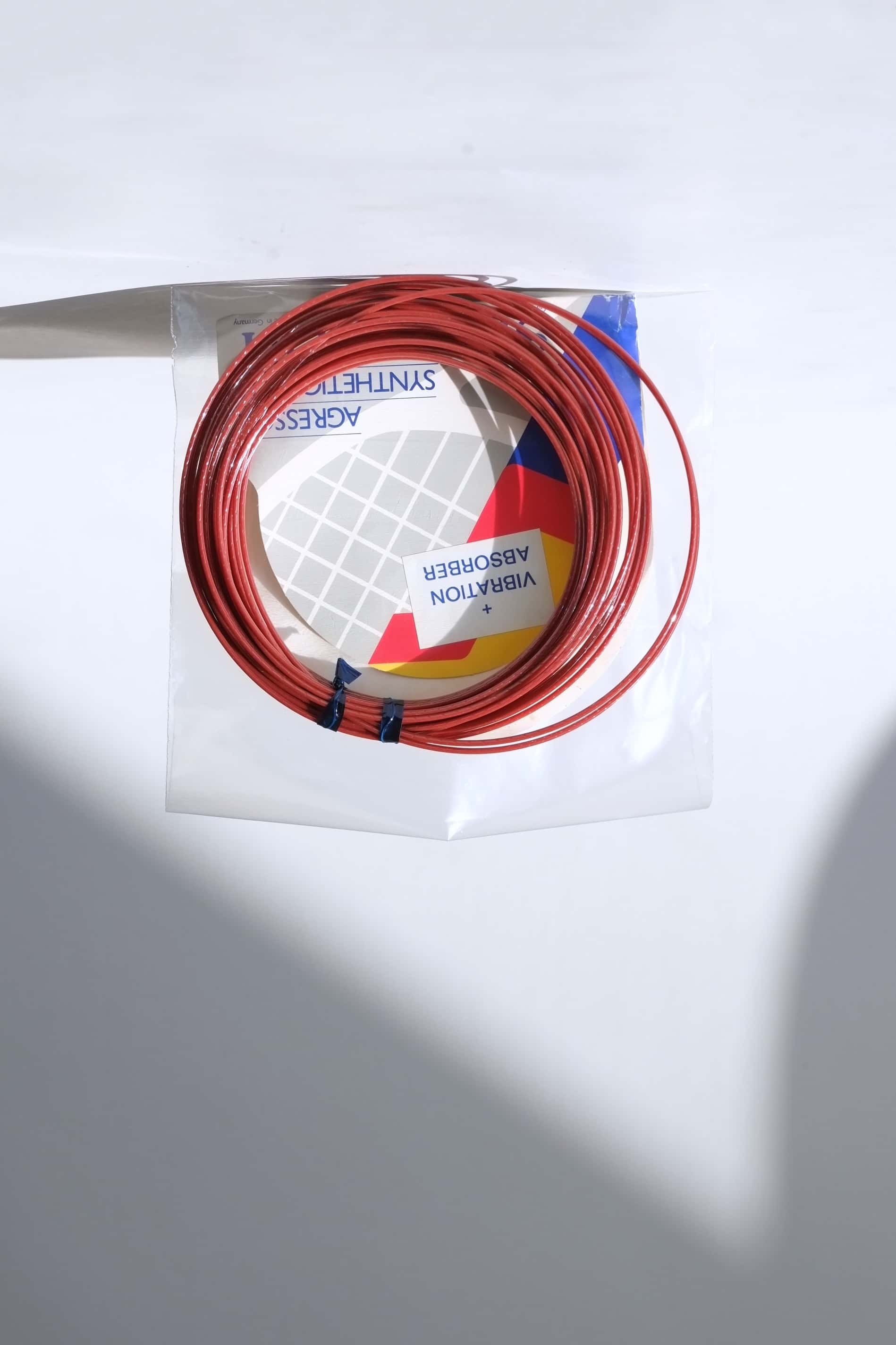 Coiled vintage Snauwaert Agressor synthetic gut tennis strings removed from the packaging to show the texture and color.