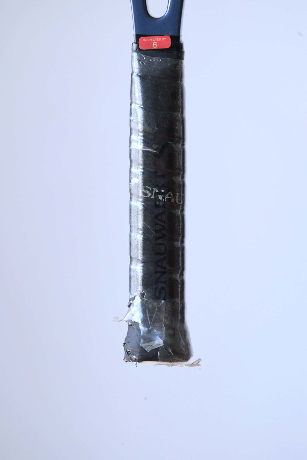 Detail shot of the racquet handle variation wrapped in a black synthetic Snauwaert grip with a red "Inspected By 6" sticker at the top.
