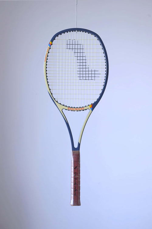 Studio full front shot of a strung early 80s Snauwaert Graphite Dyno tennis racquet with a brown leather grip, showing its signature Angled-Arc frame design.