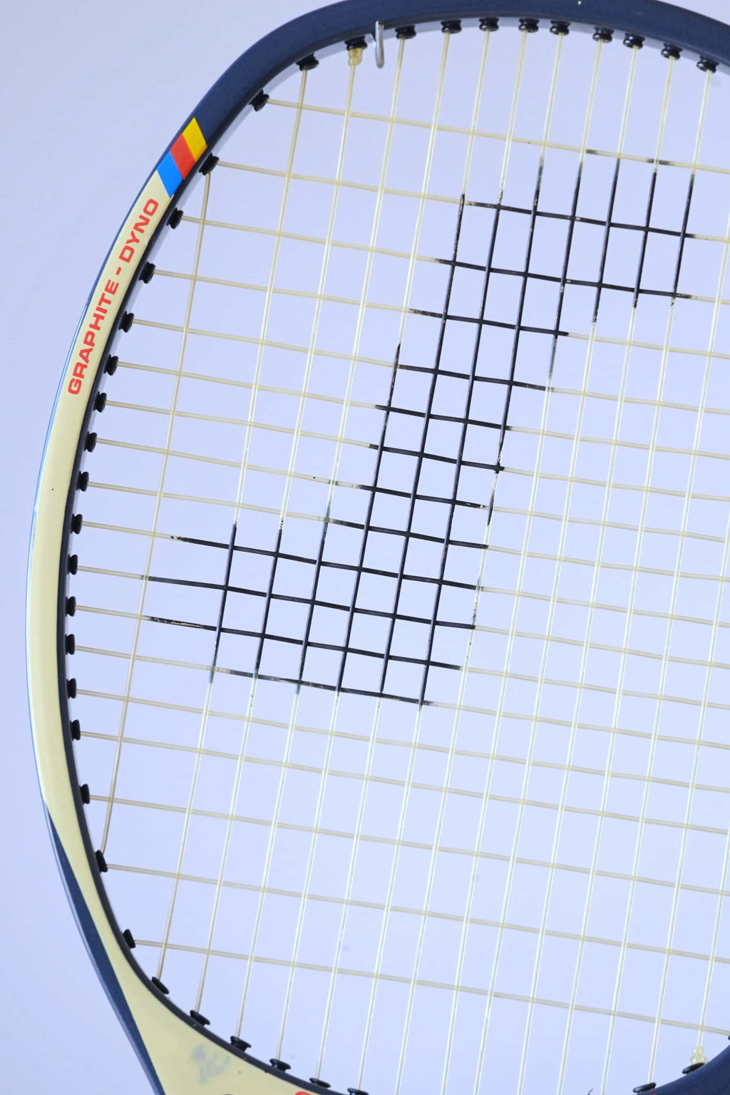 Macro view of the upper racquet hoop emphasizing the unique angled frame design and the red "GRAPHITE - DYNO" model name text.