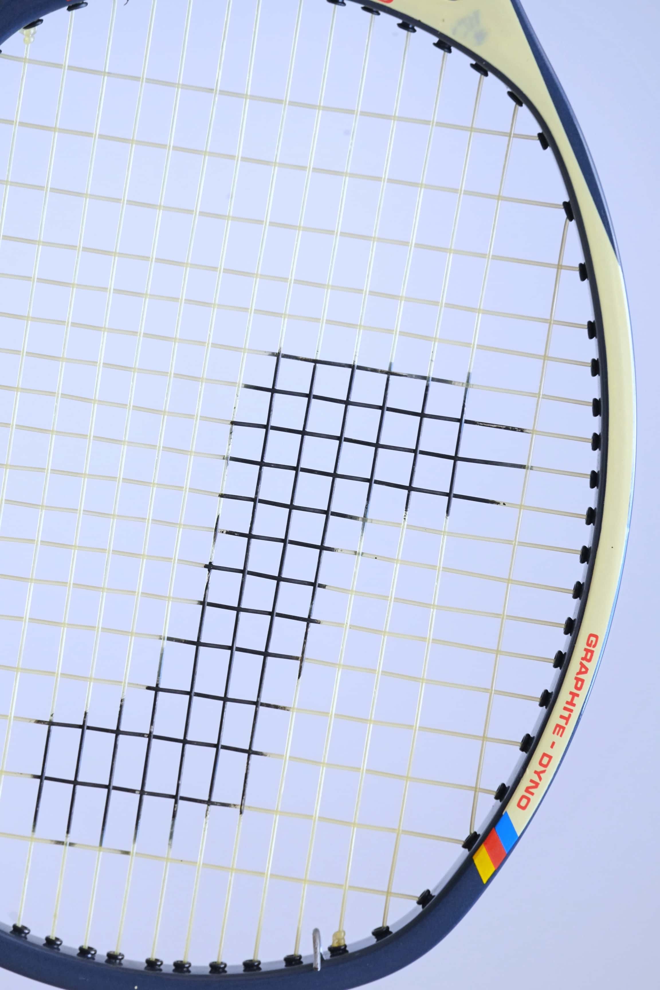 Macro view of the upper racquet hoop emphasizing the unique angled frame design and the red "GRAPHITE - DYNO" model name text.