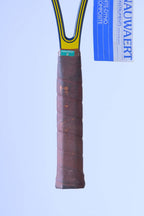 Close-up of the racquet's original brown leather grip showing minor surface wear, a green inspection sticker at the top collar, and the attached paper hang tag.